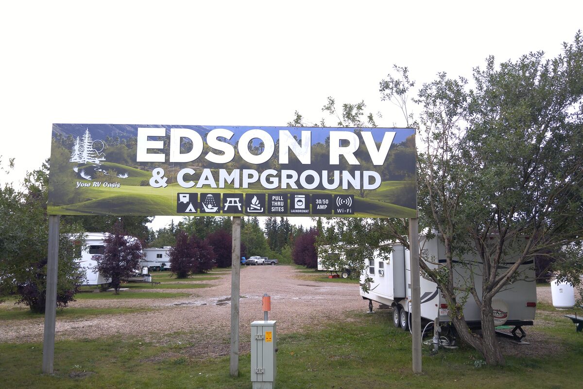 Edson RV & Campground entrance sign with park visible behind it, trees and RVs on both sides